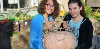 Die Schülerpraktikantinnen Liv und Theresa mit dem 14,8 Kilo-Kürbis vom UBZ. Foto: Mathias Kehren