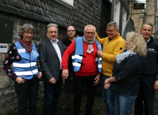 Bürgermeister Thomas Dinkelmann und Ralf Schefzig (3. v. r.) von der Kreisverkehrswacht haben Klaus Haxel eine blaue Weste übergezogen. Rechts Udo Loppnow, neben ihm Sozialamtsleiterin Anja Karp, Oliver Pahl von der Stadt (3. v. l.) und Petra Decker. Foto: Kreisstadt Mettmann