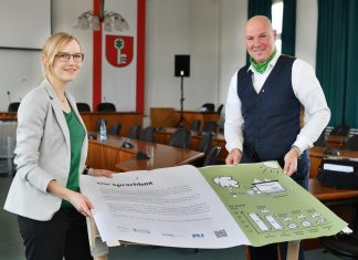 Viviane Pape und Bürgermeister Dirk Lukrafka mit einem Entwurf einer Infotafel. Insgesamt fünf dieser Art sollen bald aufgestellt und auf den jeweiligen Klimaschutz-Beitrag eines Projekts hinweisen. Foto: Mathias Kehren