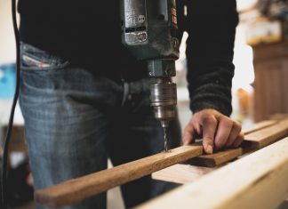 Ein Mann bohrt ein Loch in ein Holzbrett. Foto: pexels/symbolbild