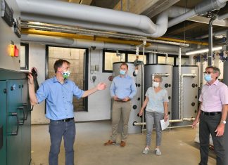 Jens Matics, Bereichsleiter Energiedienstleistungen, mit Kämmerer Björn Kerkmann, Schulleiterin Sonia Cohen und Stadtwerke-Geschäftsführer Michael Scheidtmann vor dem neuen Blockheizkraftwerk. Foto: Mathias Kehren