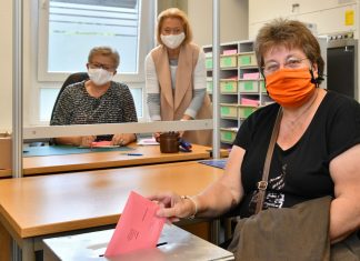 Nur mit Maske zur Wahl: Marlies Wilhelm hat ihre Stimme schon per Briefwahl abgegeben. Die Wahlhelferinnen Anneliese Klewer und Karin Eiche-Janßen erinnern an die Maskenpflicht bei der Stimmabgabe. Foto: Mathias Kehren