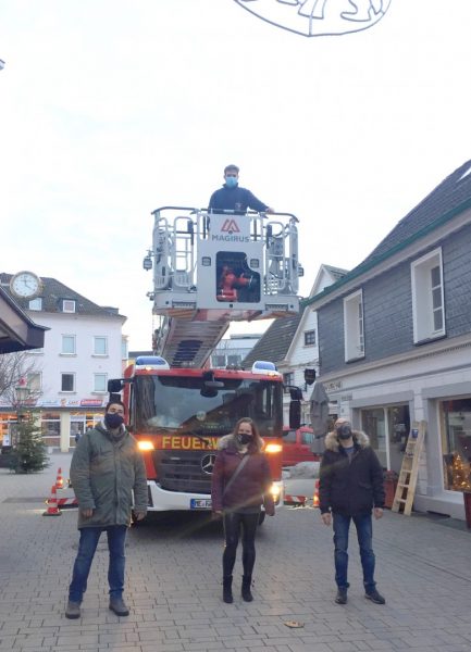 Sie freuen sich über den weihnachtlichen Glanz in der City: Emanuele Berardi, Christina Rick, Dirk Herbener (alle Vorstand Wülfrath pro e. V.), auf der Drehleiter: Niklas Sarfeld, städt. Mitarbeiter der Feuer- und Rettungswache. Foto: Stadt Wülfrath