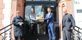 Bürgermeister Christoph Schultz und seine Stellvertretungen Regina Wedding und Mark Göckeritz bedanken sich mit einem Präsentkorb bei Lars Busch, der sich imStadtteil Hochdahl engagiert. Foto: Stadt Erkrath