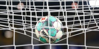 Ein Fußball liegt vor der Partie im Netz. Foto: Friso Gentsch/dpa/Symbolbild