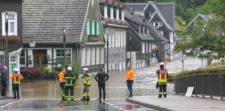 Einsatzkräfte stehen an einer überschwemmten Straße. Foto: Gianni Gattus/TNN/dpa/Archivbild