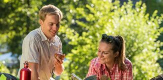 Apfel, Vollkornbrot und Blättern im Neanderland-Steig-Reiseführer - ein Paar macht es sich beim romantischen Picknick gemütlich. Foto: Kreis Mettmann/Dominik Ketz