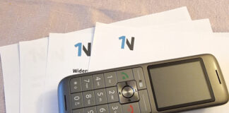 Ein Telefon liegt auf einem Werbebrief mit 1N-Logo. Foto: Verbraucherzentrale NRW