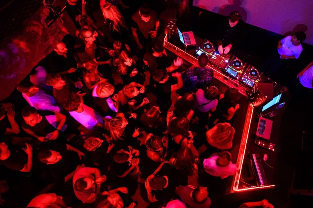 Menschen tanzen in einem Club zu elektronischer Musik.