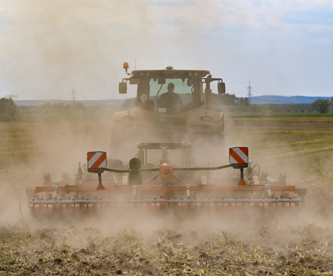 Acker Ein Landwirt bearbeitet den trockenen Boden auf einem Feld und wirbelt dabei viel Staub auf.