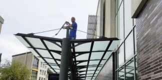 Betriebsleiter Reyis Resitoglu spritzt das Dach der Haltestelle vor dem Angermarkt ab. Foto: Stadt Wülfrath