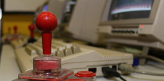 Ein Joystick steht vor einem Retro-Computer. Foto: Volkmann