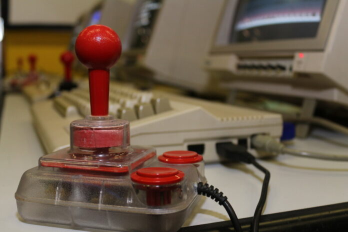 Ein Joystick steht vor einem Retro-Computer. Foto: Volkmann