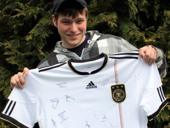 JUZ-Eggerscheidt-Besucher Andreas Harke zeigt den Hauptpreis: ein signiertes Nationaltrikot von 2010. Foto: Stadt Ratingen