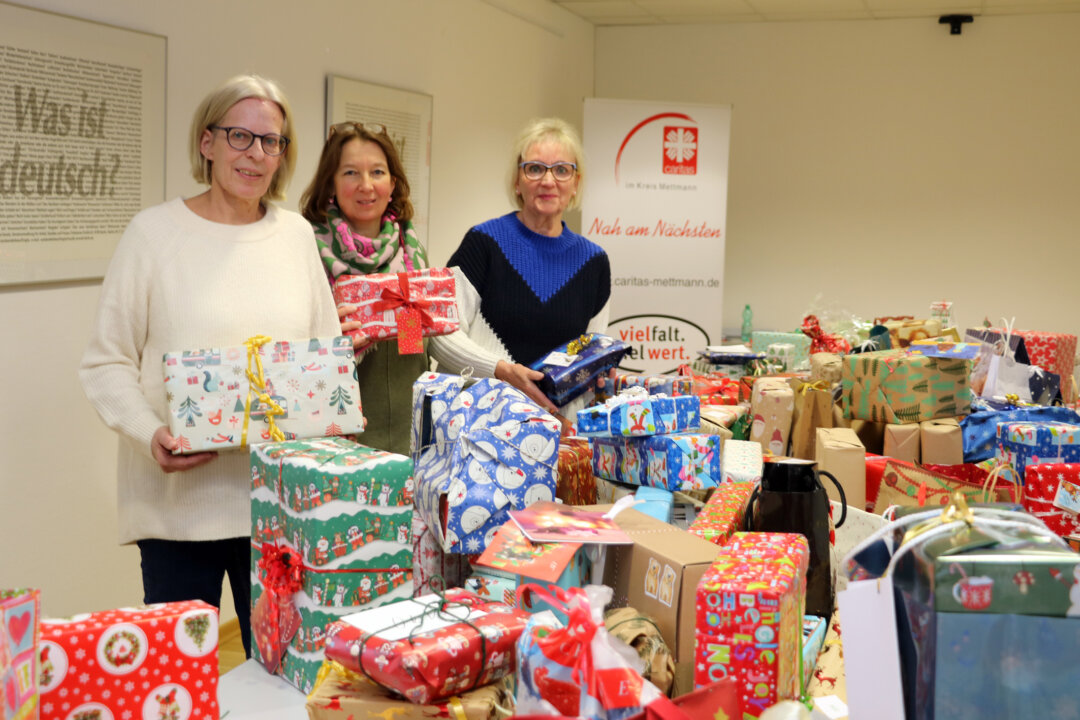 Bianca Schnee von der Caritas, Heike Hildebrandt von der Kreissparkasse Düsseldorf und die Ehrenamtlich Ingrid Drückes zeigen die vielen Geschenke. Foto: Caritas