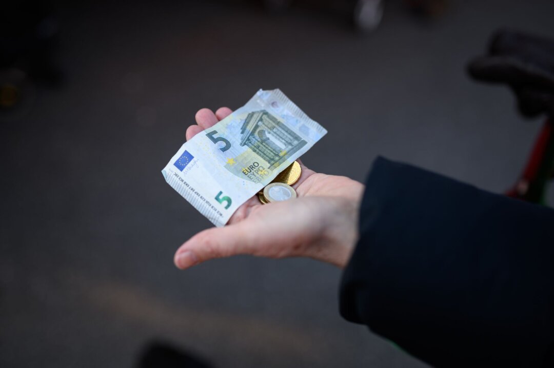 Eine Frau hält das Bargeld für ihren Einkauf in der Hand bereit.