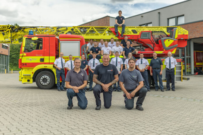 Marcel Weirauch von der Feuerwehr Langenfeld, Oliver Pofahl von der Feuerwehr Düsseldorf und Nikolai Hollenberg von der Feuerwehr Erkrath mit einer diensthabenden Wachabteilung und und Tagesdienstkräften. Foto: FW Ratingen