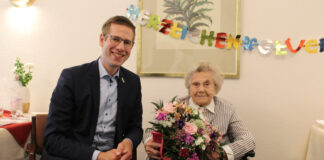 Christa Teichmann an ihrem hundertsten Geburtstag. Bürgermeister Christoph Schultz gratulierte und überreichte neben einem Strauß Blumen auch regionale Präsente. Foto: Stadt Erkrath