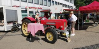 Landwirt Rolf Beckershoff im Gespräch mit zwei Marktbesucherinnen. Ein Junge sitzt auf dem alten "Schlüter" von 1966. Foto: Kreisstadt Mettmann