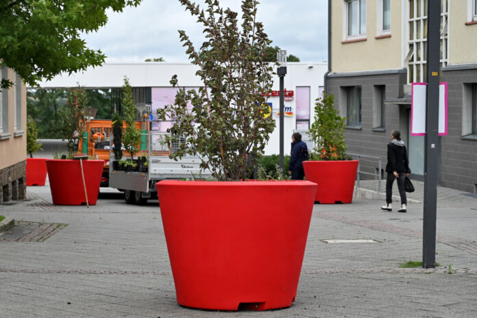 Riesengroße hellrote Blumenkübel stehen in der Innenstadt am Rathaus Heiligenhaus. Foto: Mathias Kehren