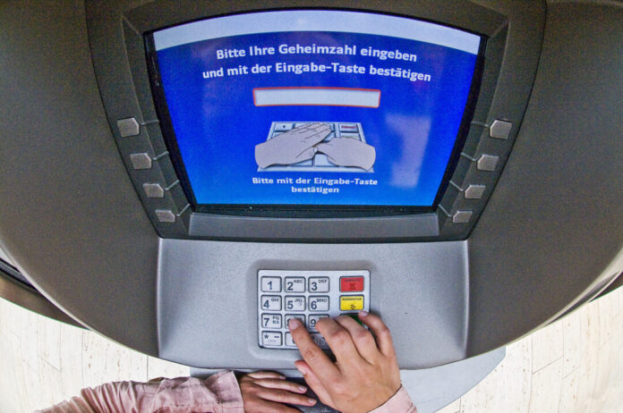 Person benutzt Geldautomaten-Tastatur.