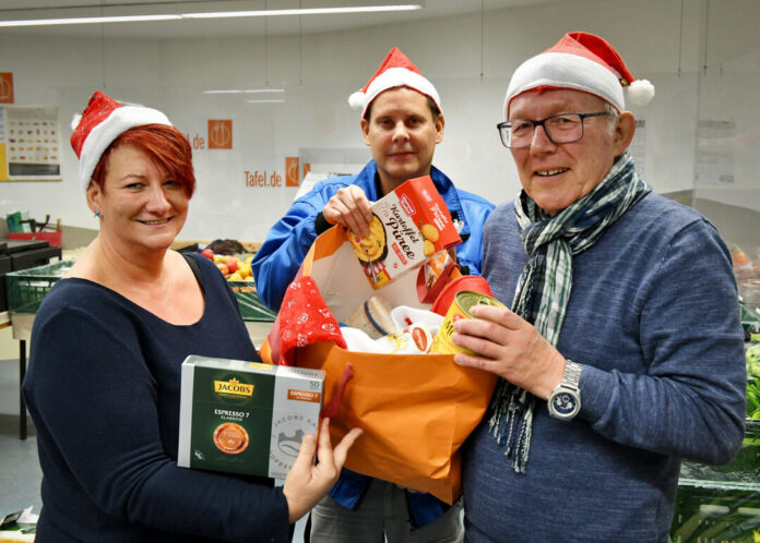 Tanja Högström, Sascha Bauer und Bernd Arnold von der Tafel Wülfrath zeigen, was in eine Weihnachtstüte hineingehört. Foto: Mathias Kehren