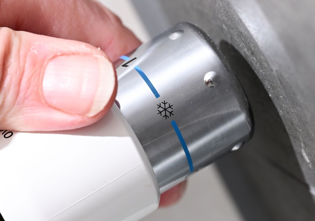 Hand stellt Thermostat auf Kühlsymbol ein.