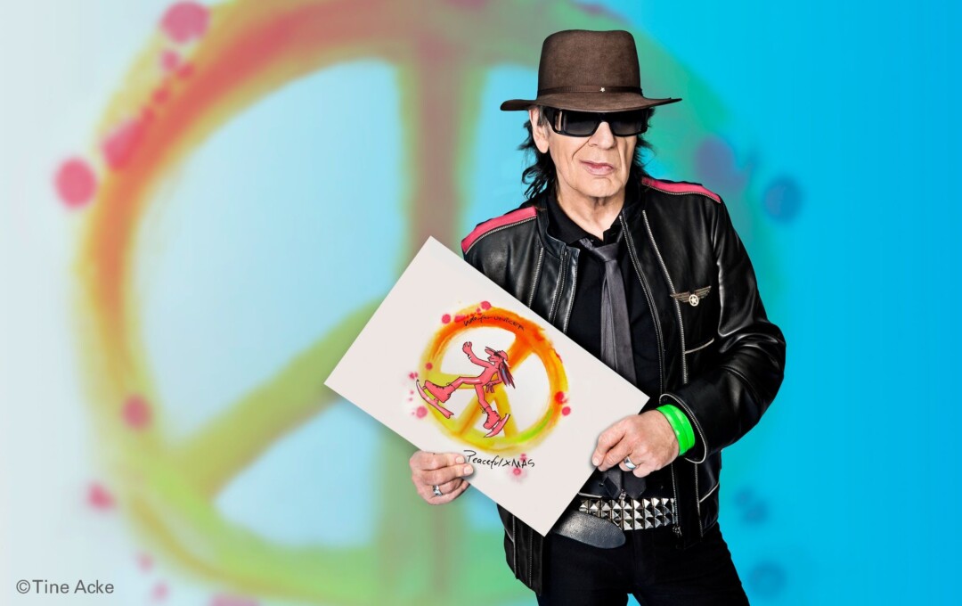 Mann in Lederjacke hält buntes Kunstwerk.