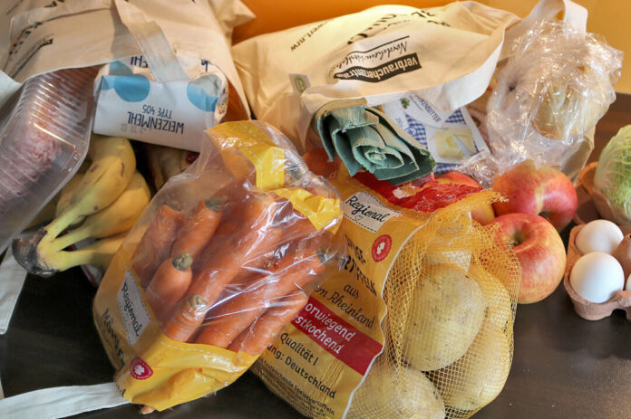 Einkaufstaschen mit verschiedenen Lebensmitteln auf einer Küchenarbeitsplatte.