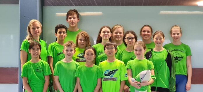 Jugendliche Schwimmteam in grünen Shirts gruppenfoto.