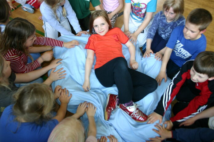 Kinder spielen zusammen auf blauer Decke.