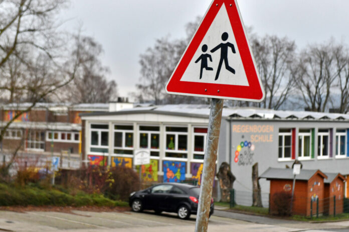 Verkehrsschild Achtung Kinder, Schule im Hintergrund