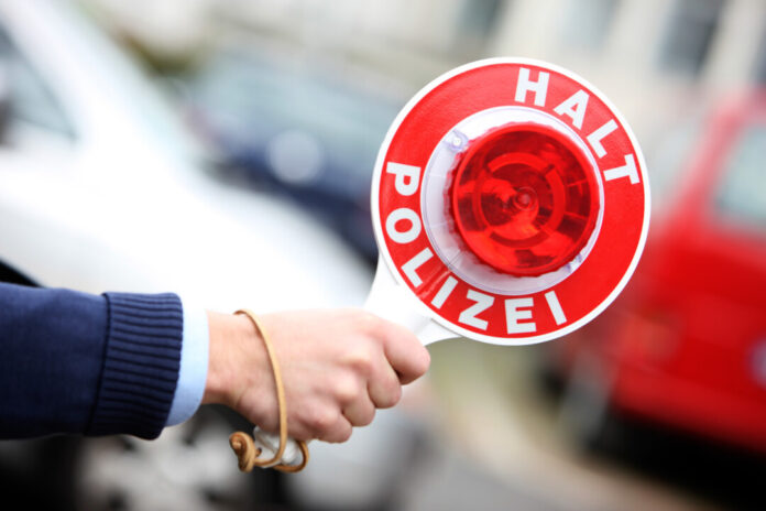 Polizei-Kelle zeigt "Halt" Signal.