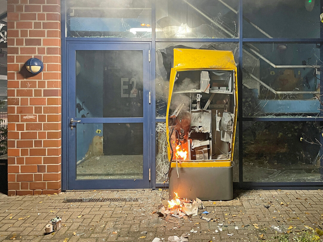 Zerstörter Automat vor beschädigtem Gebäude bei Nacht.
