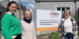 Drei Personen vor BDH-Bürogebäude mit Schild.