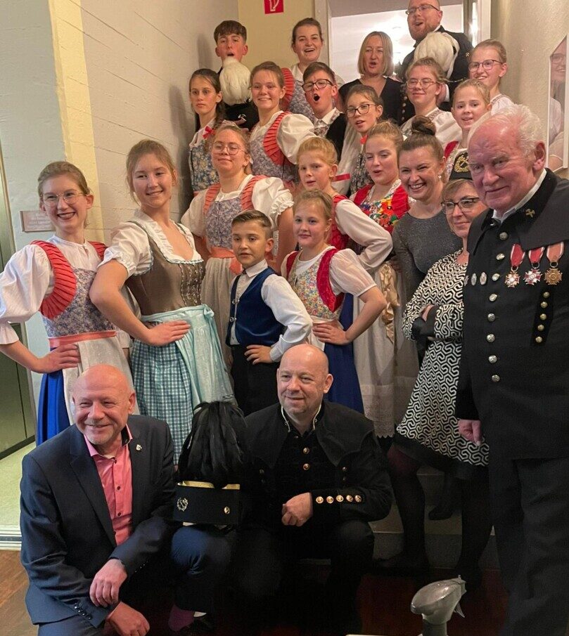 Gruppe in traditioneller Tracht posiert lächelnd innen.