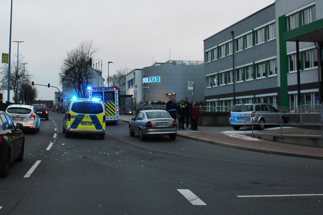 Polizeieinsatz vor Polizeistation mit Rettungsfahrzeug.