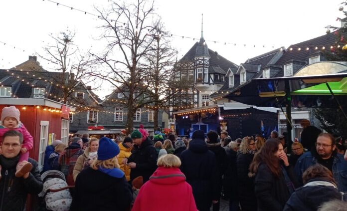 Weihnachtsmarkt mit Menschen und Beleuchtung.
