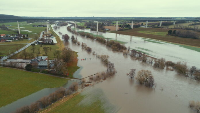 Hochwasser überflutet ländliche Gegend nahe Brücke.