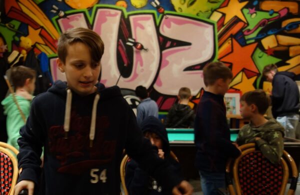 Junge vor Graffiti-Wand mit Freunden.