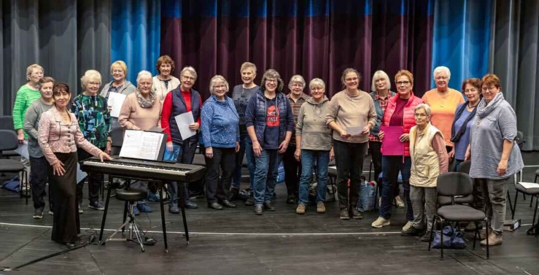 Chorgruppe posiert auf Bühne mit Klavier