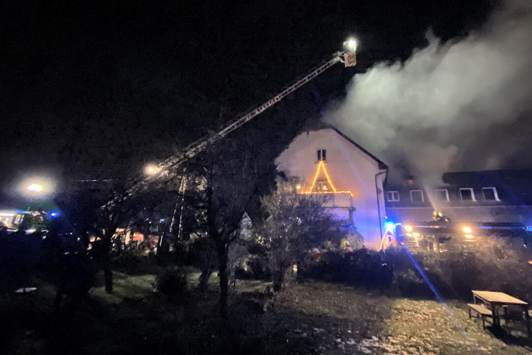 Feuerwehr löscht nächtlichen Hausbrand mit Drehleiter.