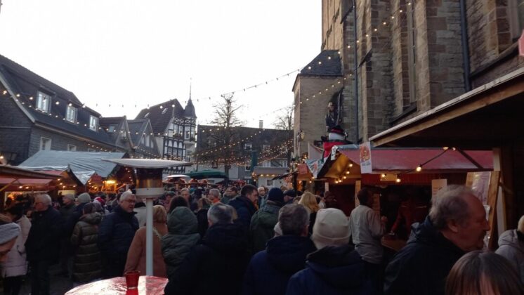 Weihnachtsmarkt mit Menschen und Fachwerkhäusern.