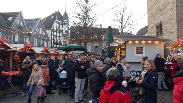 Weihnachtsmarkt mit Menschen und Fachwerkhäusern.