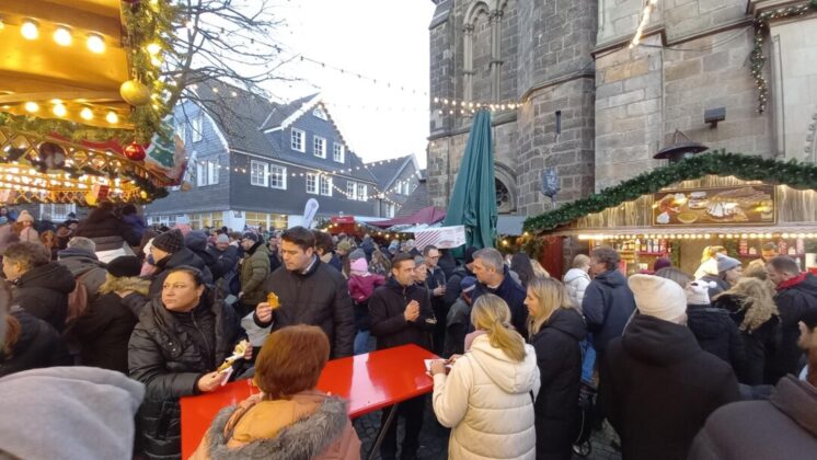 Weihnachtsmarkt mit Menschen und festlichen Ständen.