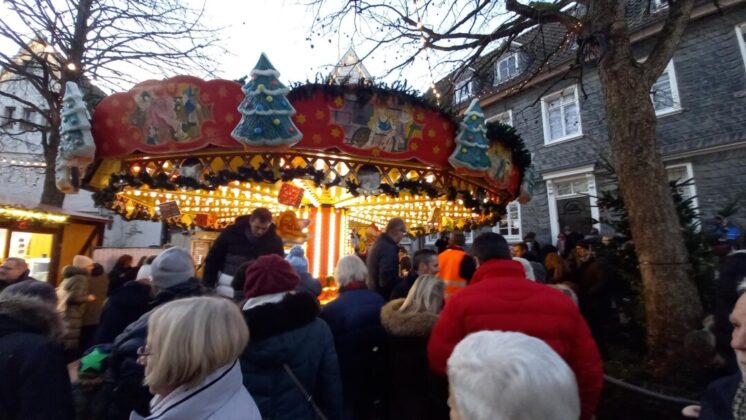 Weihnachtsmarkt Karussell und Besucher bei Dämmerung.