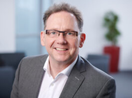 Kreis Mettmann: Wenig Bewegung zum Jahresende auf dem Arbeitsmarkt Mann mit Brille im Büro lächelt.