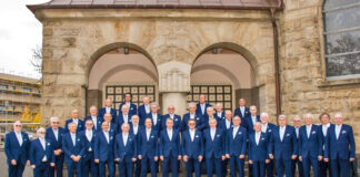 Männerchor in Anzug vor historischem Gebäude.