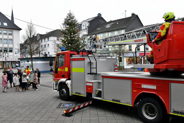 Feuerwehr dekoriert Weihnachtsbaum mit Drehleiter in Stadtzentrum.