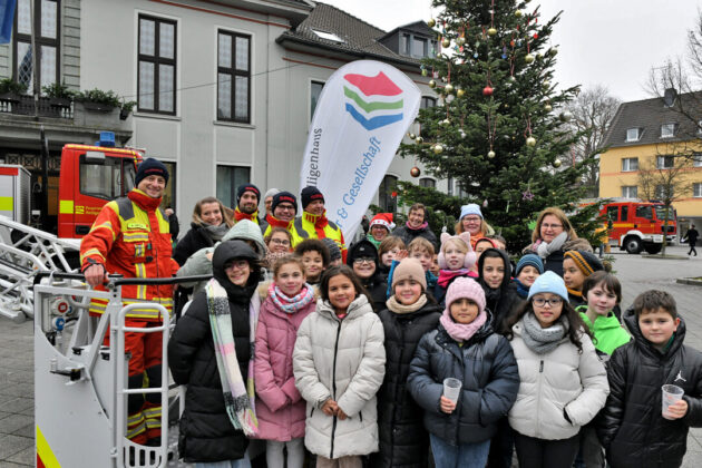 Gruppe vor Weihnachtsbaum mit Feuerwehrleuten.